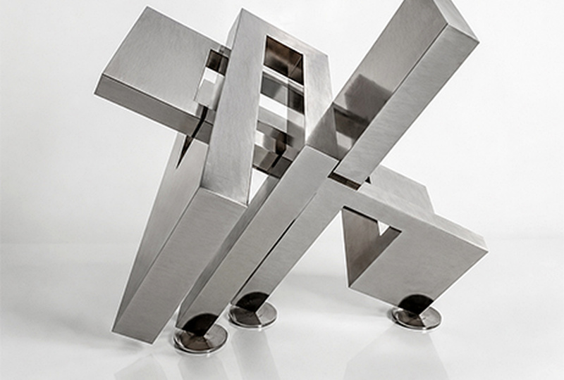 Sculpture abstraite géométrique en inox poli sur fond blanc